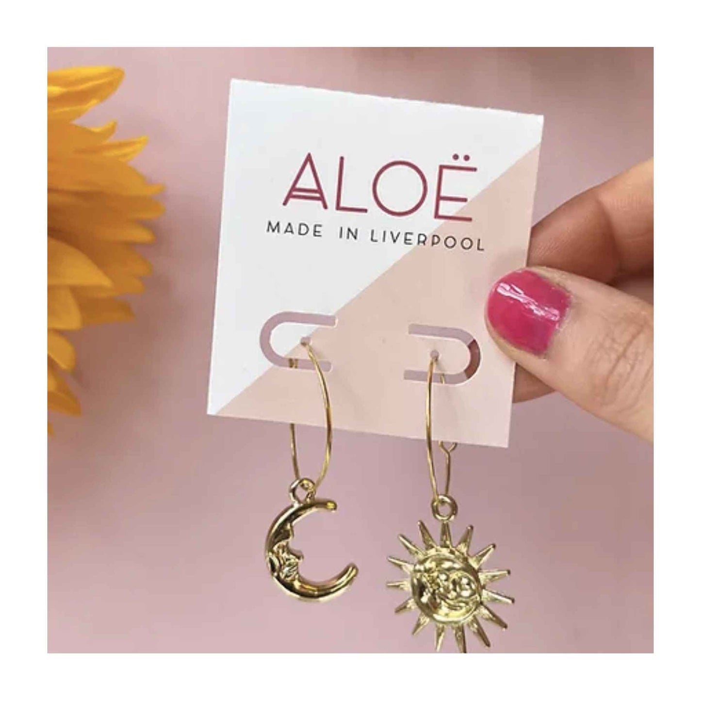 Gold plated hoop earrings from ALOE jewellery. One earring is a crescent moon with face and the other is a full sun with rays and face.